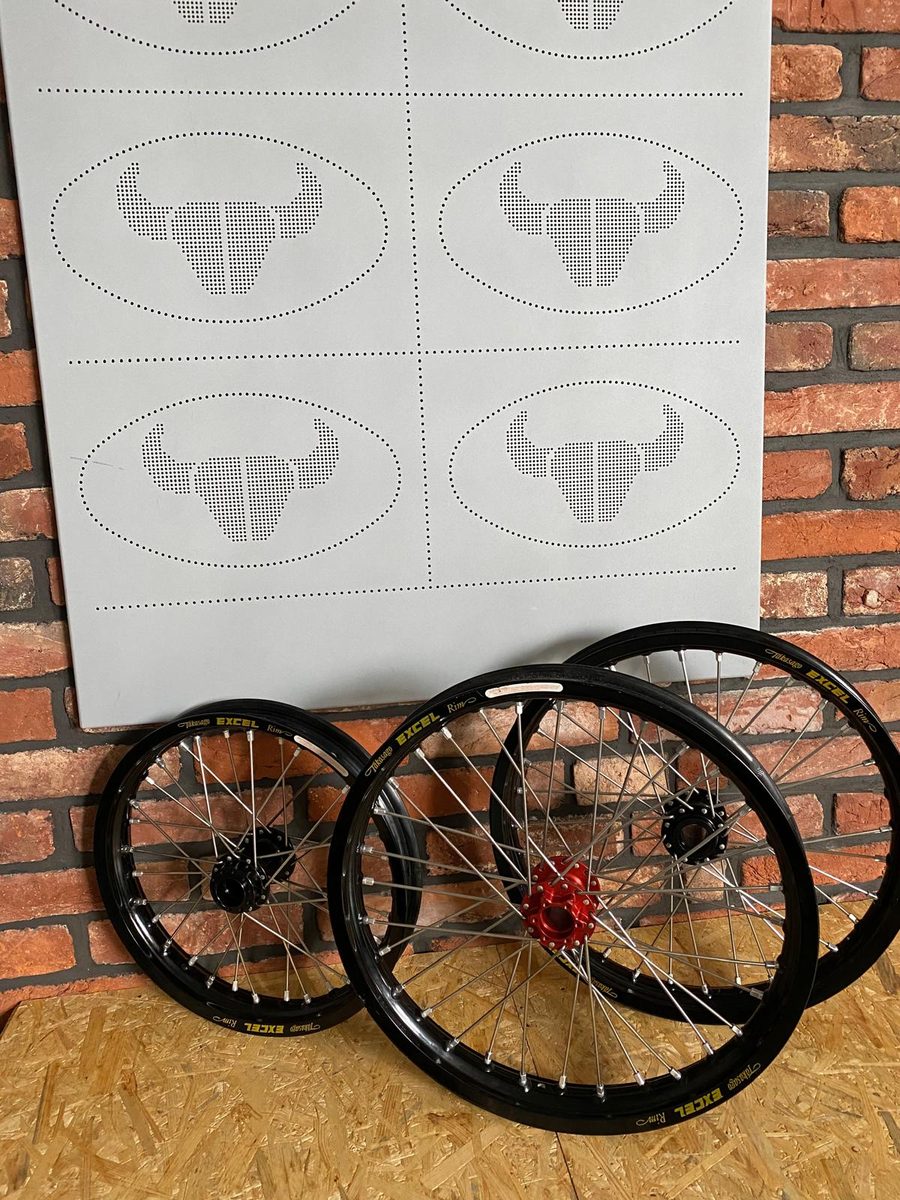 Three revX electric motorcycle wheels with Excel rims in front of the Beran Tuning logo wall
