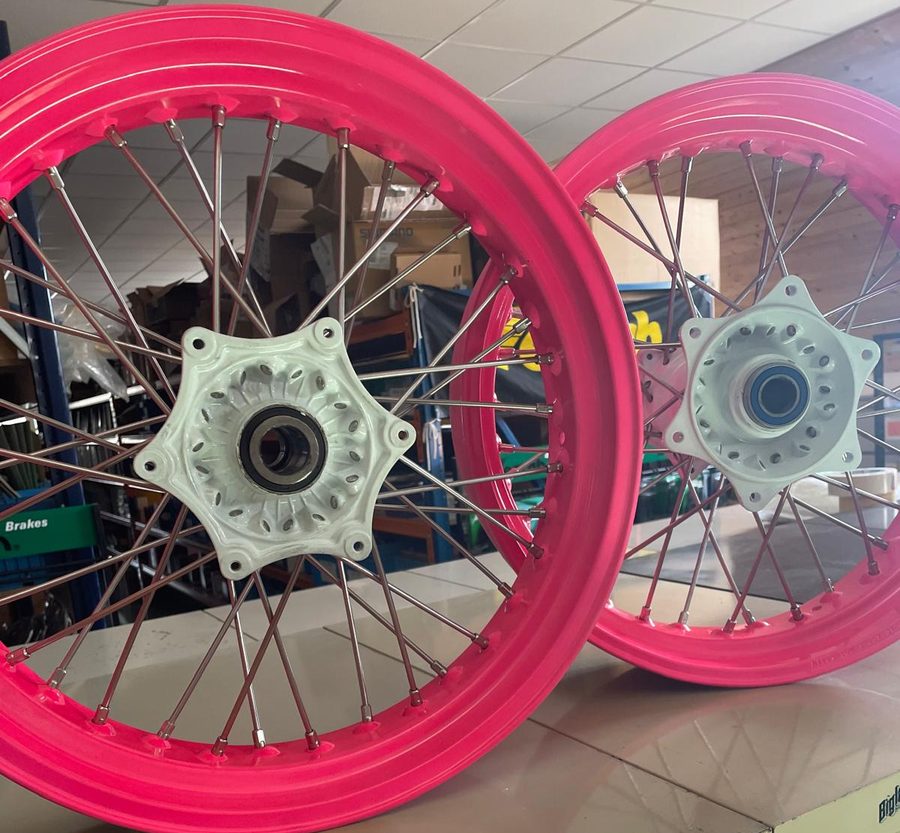 Two Yamaha YZ 450 wheels with neon pink rims and white hubs